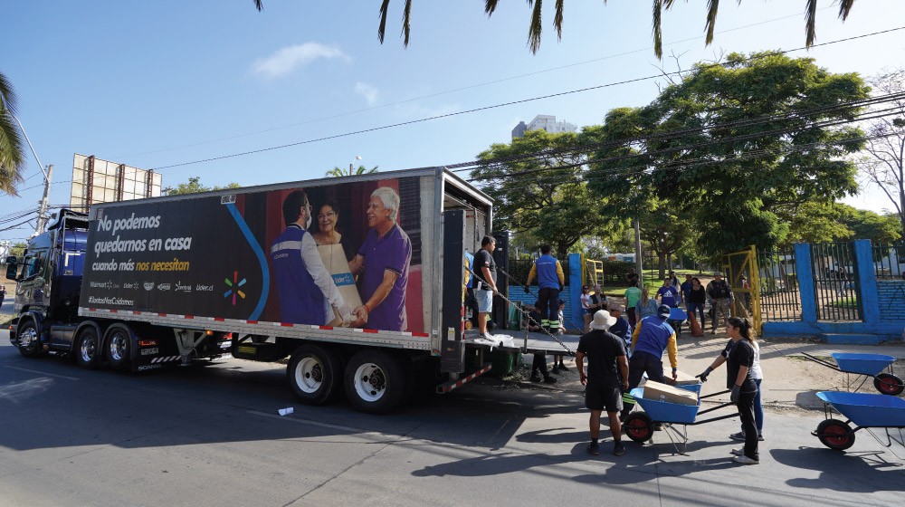Image shows Walmart Chile truck being unloaded by a group of people.