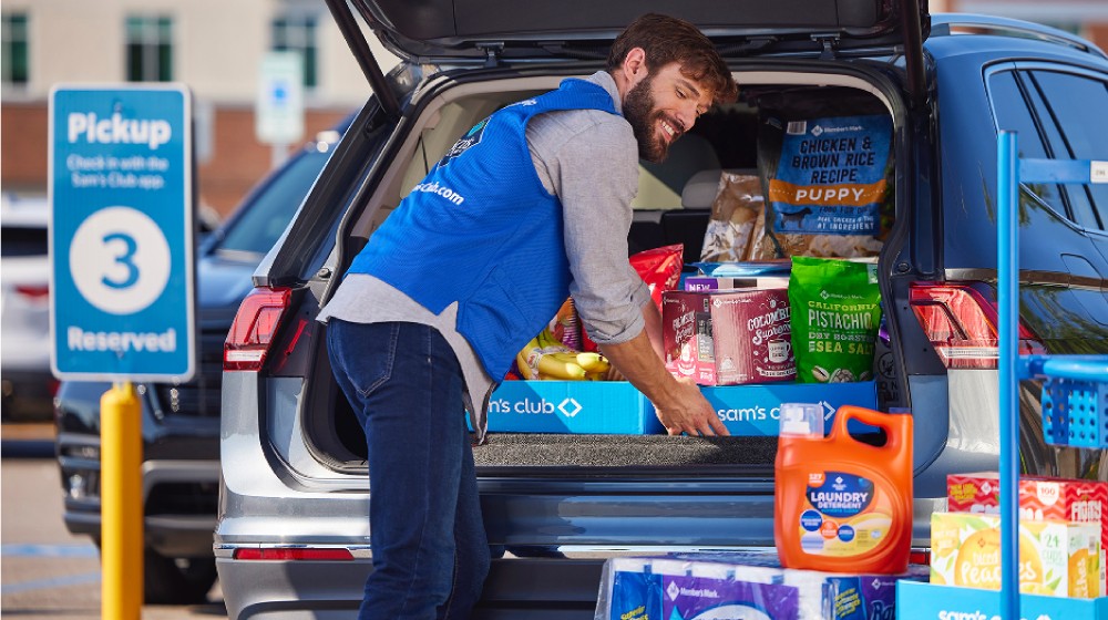 A Sam's Club associate loads a large pickup order into the back of a sport utility vehicle.