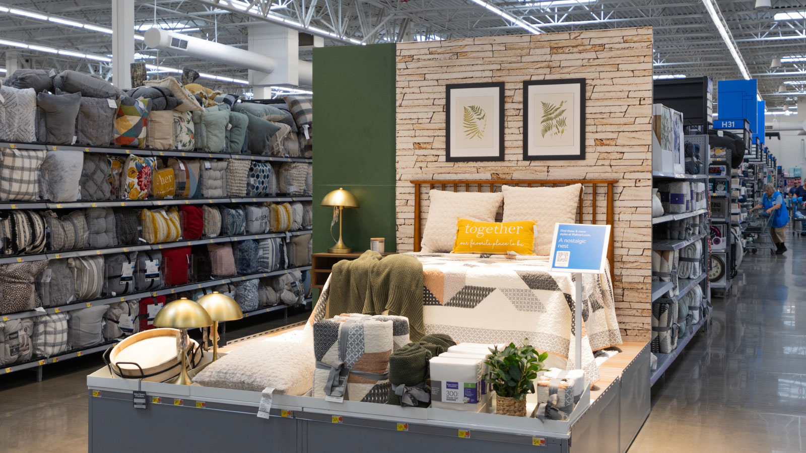 Bedroom decor display in store home department showing bed, bedding, night stand, pillows and accessories.
