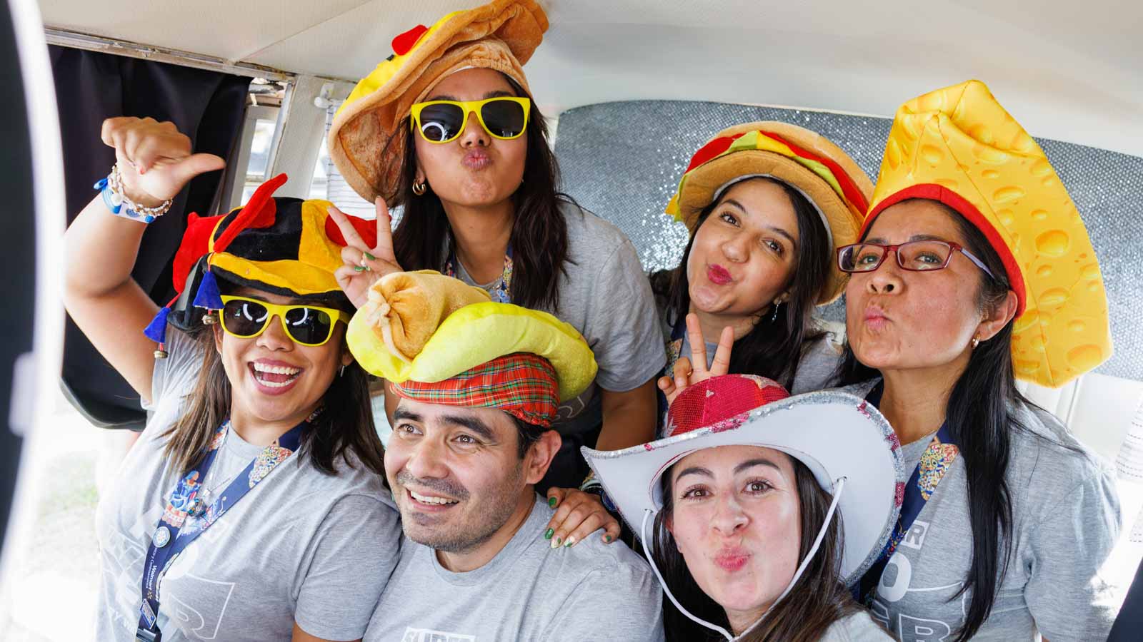A group of associates wear funny hats and smile at the camera.