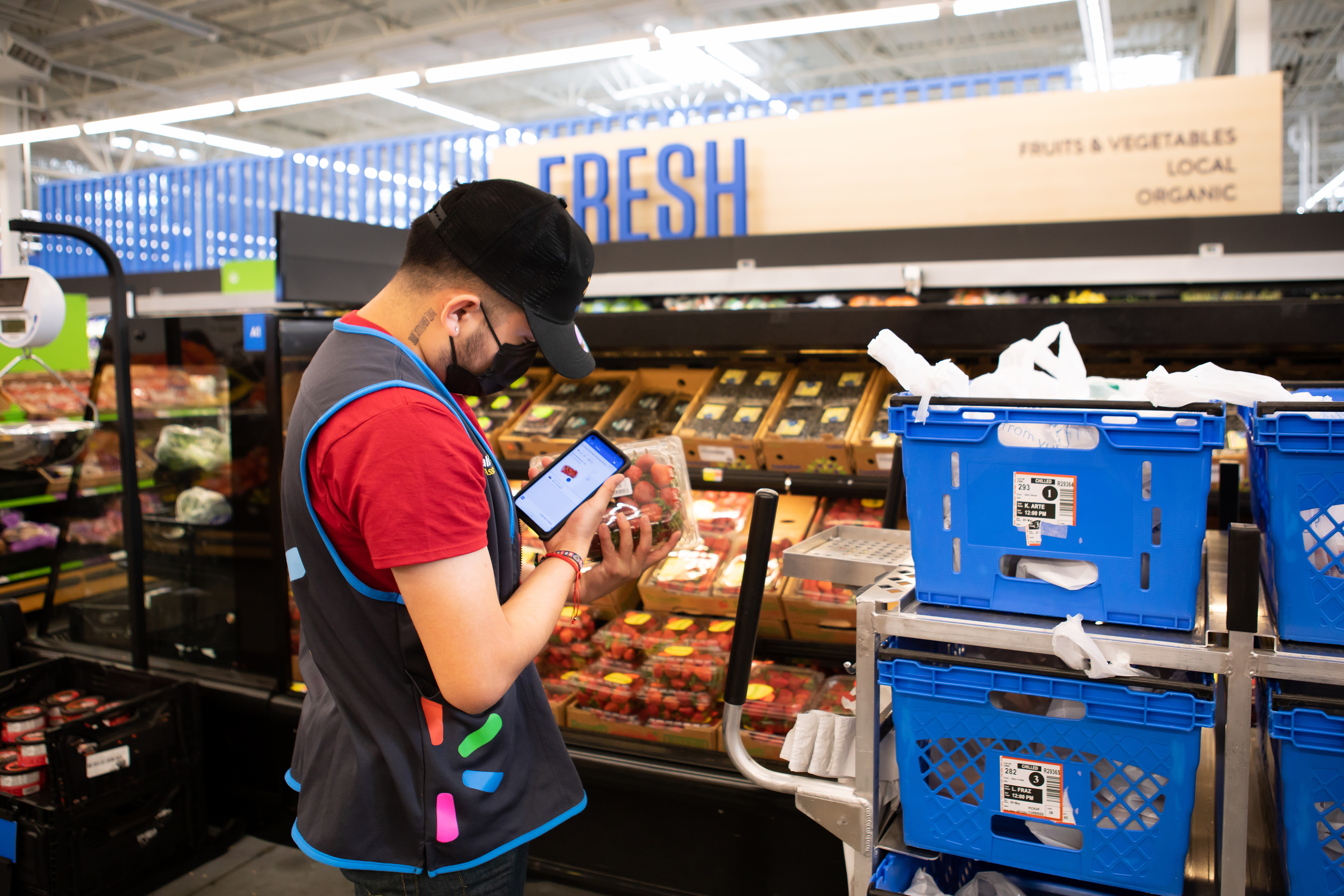 A masked Walmart associate scans strawberries for a pickup order