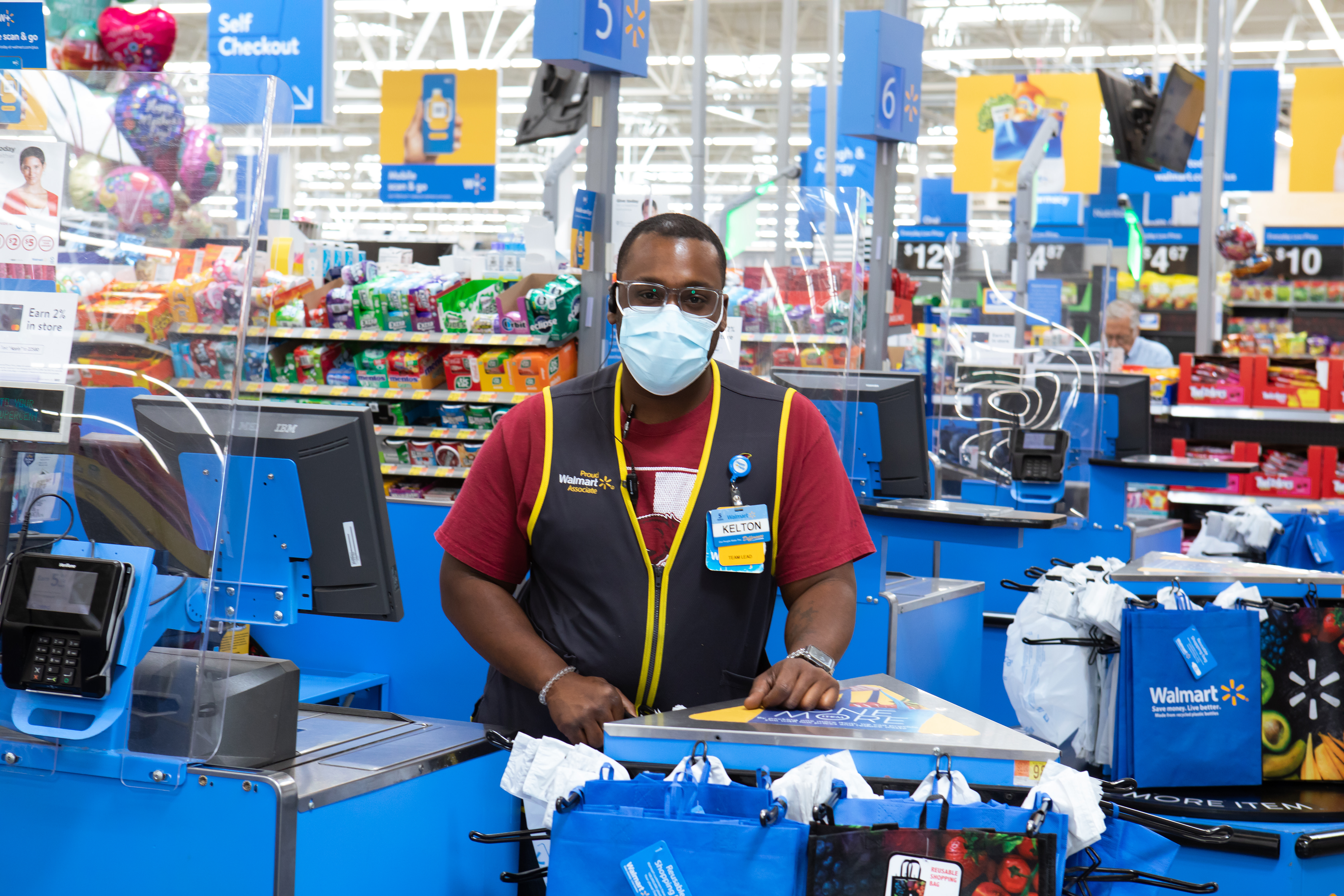 Walmart associate Kelton wears a mask at a checkout register