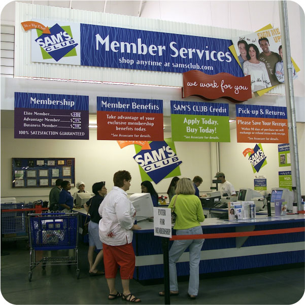 Photo of people standing in a queue in front of Member Services counter at a Sam's Club. 